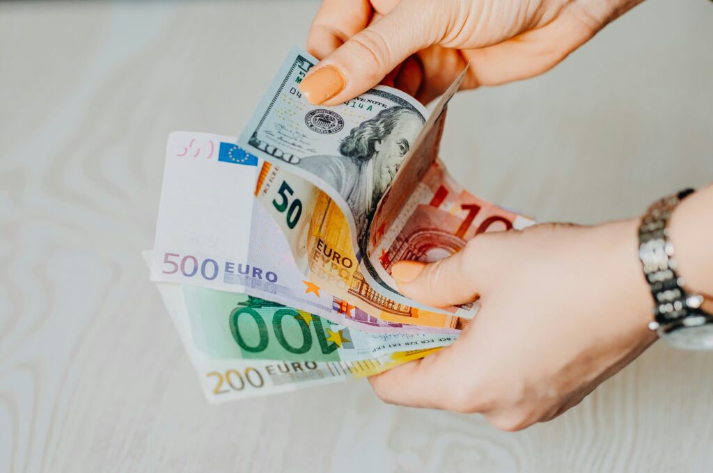 Euró és dollár bankjegyeket tartó kéz, amely a hagyományos, készpénzes pénzváltást szemlélteti.