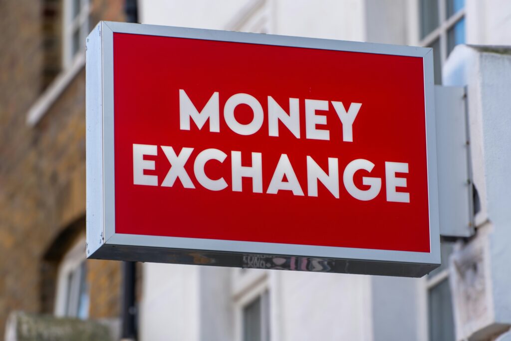 Piros neonreklám „Money Exchange” felirattal egy hagyományos pénzváltó üzletnél.